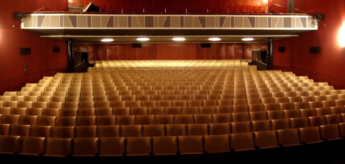 Der Zuschauerraum des Gloria-Theaters mit vielen Stühlen in vielen Reihen und Beleuchtung.