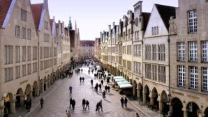 Auf dem Foto sieht man die Altstadt von Müster mit einigen Marktständen und Fußgängern.