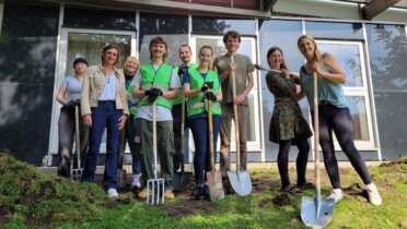 Auf dem Foto sieht man neun Personen, die mit Harken und Spaten vor einem Gebäude stehen. Beim Auftakt der Deutschen Aktionstage Nachhaltigkeit pflanzten Freiwillige Blumenwiesen, Seedbombs und hängten Vogelhäuser auf dem Campus der Universität Hamburg auf. Foto: Myriam Rapior